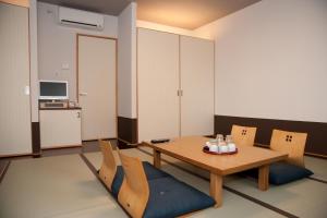 a room with a table and chairs and a television at Hakata Sunlight Hotel Hinoohgi in Fukuoka