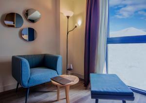 a living room with a blue chair and a window at Gudauri Lodge in Gudauri