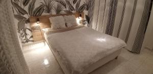 - un lit avec des draps et des oreillers blancs dans une chambre dans l'établissement Les Grands Cedres, à Nice