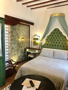 a bedroom with a bed with a green headboard and a table at Retiro del Teatro Almagro in Almagro