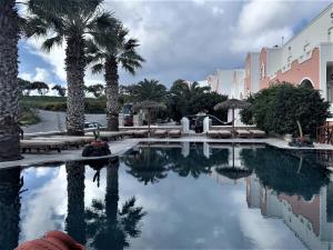 una piscina con palmeras y un edificio en Villa Manos Hotel en Karterados