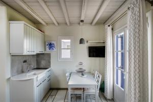 ナウサにあるPURE WHITE 1BD house with amazing Sea Views in Naousaのキッチン(白いテーブル、椅子付)、窓