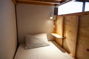 a small room with a bed with a window at Fukuoka Guesthouse SHIP in Fukuoka +30 photos