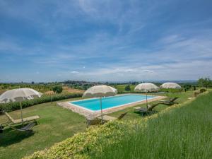 an outdoor swimming pool with umbrellas and chairs at Holiday Home Vanessa by Interhome in Castelnuovo Berardenga