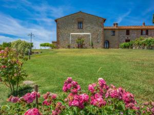 an old stone house with pink flowers in the yard at Holiday Home Vanessa by Interhome in Castelnuovo Berardenga