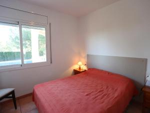 a bedroom with a red bed and a window at Villa Villa Alguer by Interhome in Les tres Cales +19 photos