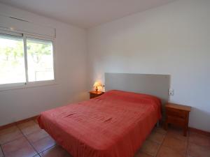 a bedroom with a red bed and a window at Villa Villa Alguer by Interhome in Les tres Cales