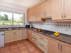 a kitchen with wooden cabinets and a sink and a window at Villa Villa Alguer by Interhome in Les tres Cales