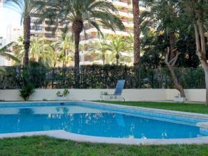 een zwembad in een tuin met palmbomen en een gebouw bij Apartment Waldorff by Interhome in Benidorm