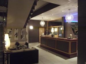 a lobby with a bar in a restaurant with chandeliers at Hôtel Restaurant de L'Europort in Saint-Avold