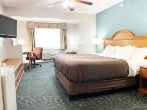 a hotel room with a bed, chair, desk and television at Countryside Suites Lincoln I-80 in Lincoln