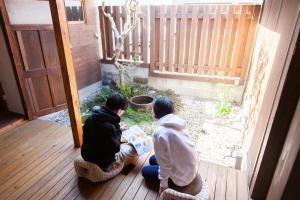 two people sitting on a porch looking at a plant at Fukuoka Guesthouse SHIP in Fukuoka