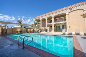 a swimming pool with chairs and a building at Howard Johnson by Wyndham Buena Park in Buena Park
