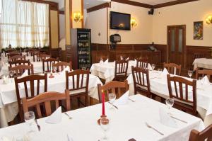 un restaurante con mesas blancas y sillas con copas de vino en Marika, en Dragobrat