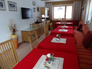 ein Esszimmer mit zwei roten Tischen und einem TV in der Unterkunft Haus Karl's Ruh in Ehrwald