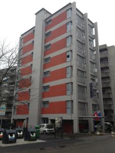ein rotes und graues Gebäude mit davor geparkt in der Unterkunft Residence Tell in Chiasso