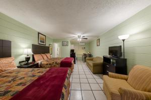 a hotel room with two beds and a flat screen tv at Sunshine Inn & Suites Venice, Florida in Venice