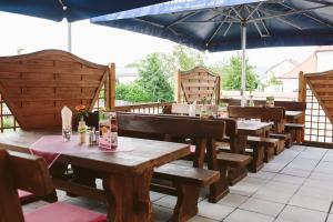 ein Restaurant mit Holztischen und einem blauen Sonnenschirm in der Unterkunft Gasthof Krone Ochsenfeld in Ochsenfeld