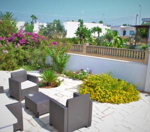 d'une terrasse avec des tables, des chaises et des fleurs. dans l'établissement I 7 Peccati, à Marina di Mancaversa