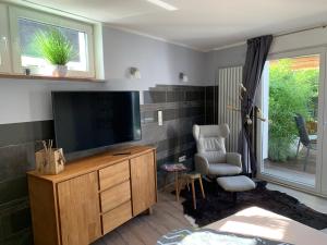 a living room with a flat screen tv and a chair at Stadtvilla Intzeplatz - Apartment Rügen in Remscheid