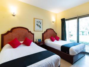um quarto com 2 camas com almofadas vermelhas e uma janela em Capital O Hotel Vitale em León