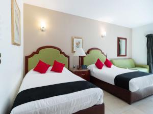 duas camas num quarto de hotel com almofadas vermelhas e pretas em Capital O Hotel Vitale em León