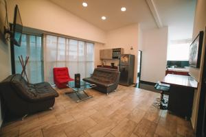 a living room with two couches and a red chair at Provenza Lofts in Medellín