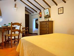 een slaapkamer met een bed, een tafel en een stoel bij Acogedora casa rural en Zahara de la Sierra in Zahara de la Sierra