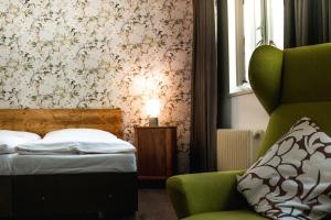 a bedroom with a bed and a green chair at Hotel Kouty in Ledeč nad Sázavou