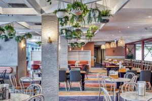 un restaurante con mesas, sillas y macetas en Ibis Styles The Entrance, en The Entrance