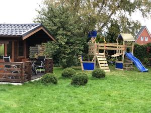 a playground with a slide and a play house at Ferienhaus Nordseerobbe in Friedrichskoog