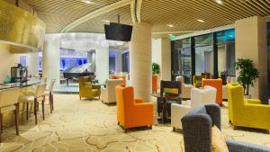 un hall avec des chaises et des tables colorées dans un bâtiment dans l'établissement Holiday Inn Taicang City Centre, an IHG Hotel, à Taicang