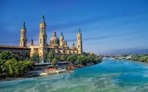 ein Gebäude mit Türmen und einer Brücke über einen Fluss in der Unterkunft EXCLUSIVO TAPAS EL TUBO CHECKIN 24H Centro 1 in Saragossa