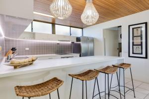 a kitchen with a white counter and stools at Nautilus Beachfront Villas & Spa in Coffs Harbour