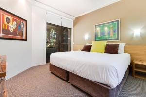 a bedroom with a large bed and a painting on the wall at Nautilus Beachfront Villas & Spa in Coffs Harbour