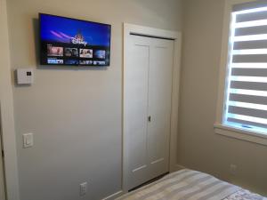 a bedroom with a tv on the wall and a bed at Mollys Cottage-The Suite on Vancouver Island near YYJ Airport and the WA and BC Ferries in North Saanich