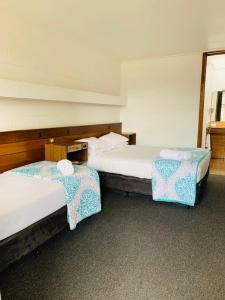 two beds in a room with at Caledonian Hotel Motel in Hamilton