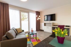 een woonkamer met een bank en een tv bij Hotel & Apartments Leugermann in Ibbenbüren