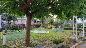un parque con parque infantil con un árbol y columpios en Beauty Monroe B&B-可包棟-150吋投影-唱歌-夏日玩水-烤肉-電動麻將 en Wujie
