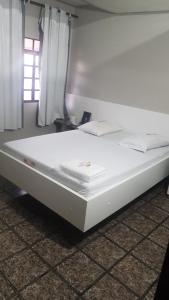 a large white bed in a room with a window at Hotel Hawai in Ceilândia