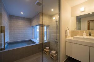 ein Bad mit einer Badewanne, einem Waschbecken und einer Dusche in der Unterkunft Chalet Luma by H2 Life in Niseko