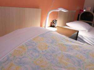 a bed with a blanket with flowers on it at Hotel Asahi Grandeur Fuchu in Fuchu