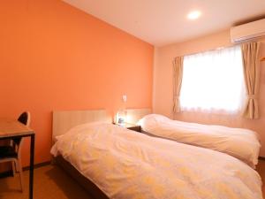 a bedroom with two beds and a window at Hotel Asahi Grandeur Fuchu in Fuchu