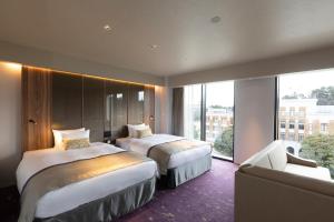 a hotel room with two beds and a couch at First Hotel Kanazawa in Kanazawa