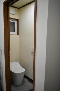 a bathroom with a toilet and a tv on the wall at Villa 777 Hakuba in Hakuba
