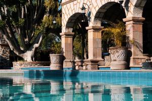 a swimming pool in front of a building with arches at Hotel Ex Hacienda La Pitaya Querétaro in Villa del Pueblito