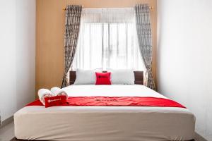 a bedroom with a bed with red sheets and a window at RedDoorz Syariah near Stadion Teladan Medan in Medan