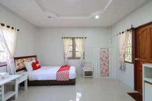 Schlafzimmer mit einem Bett, einem Schreibtisch und Fenstern in der Unterkunft OYO 553 Kongsup Resort in Lamphun