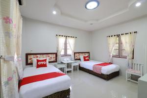 a bedroom with two beds with red and white pillows at OYO 553 Kongsup Resort in Lamphun