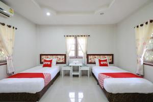 2 camas en una habitación con paredes y ventanas blancas en OYO 553 Kongsup Resort en Lamphun